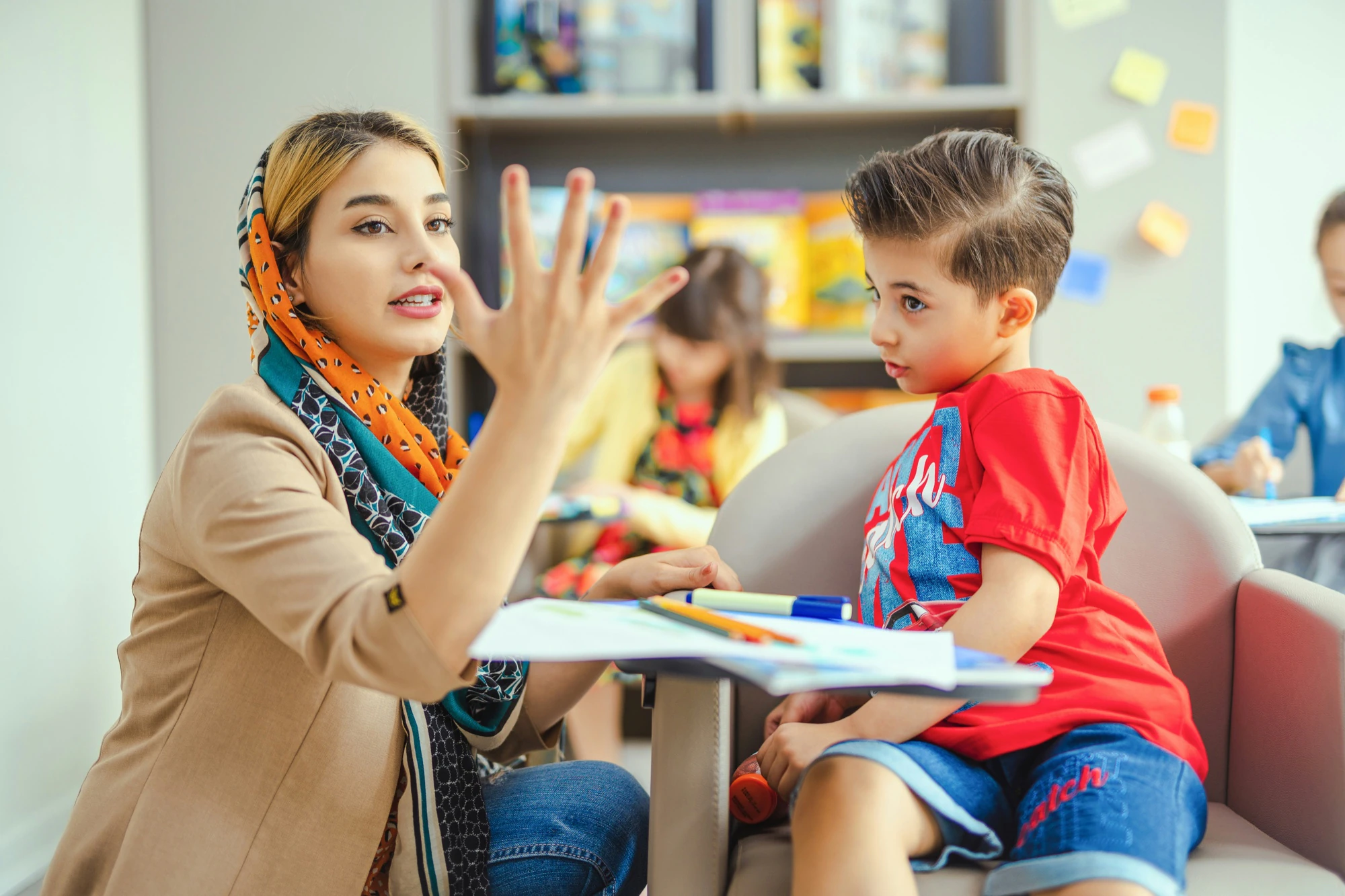 A therapist counts on her fingers with a young boy during a session.